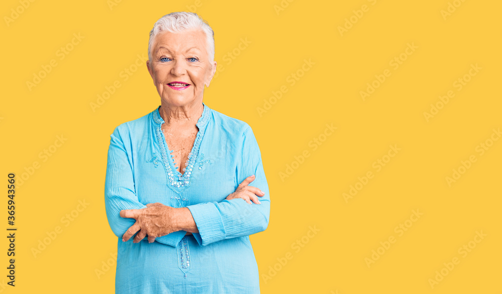 Senior beautiful woman with blue eyes and grey hair wearing summer dress happy face smiling with crossed arms looking at the camera. positive person. Senior beautiful woman with blue eyes and grey hair wearing summer dress happy face smiling with crossed arms looking at the camera. positive person.