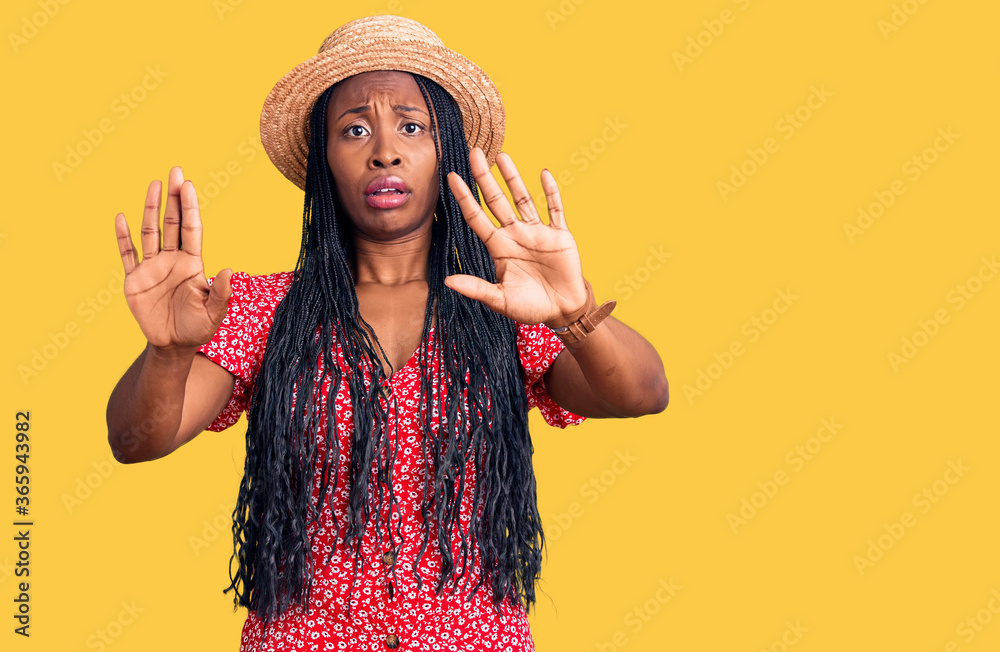 Young african american woman wearing summer hat doing stop gesture with hands palms, angry and frustration expression Young african american woman wearing summer hat doing stop gesture with hands palms, angry and frustration expression