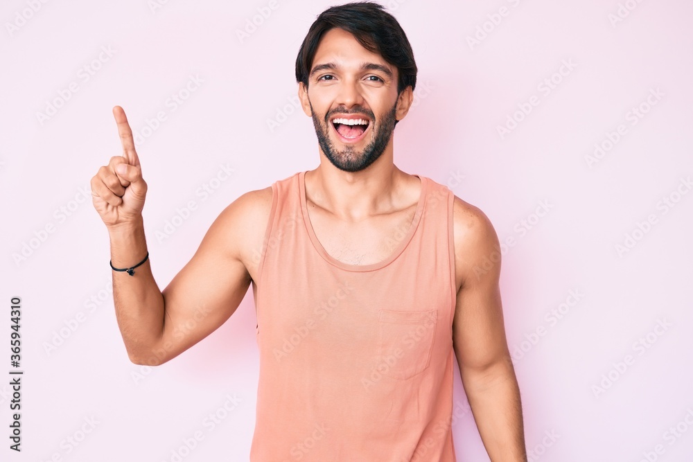 Handsome hispanic man wearing casual clothes pointing finger up with successful idea. exited and happy. number one. Handsome hispanic man wearing casual clothes pointing finger up with successful idea. exited and happy. number one.