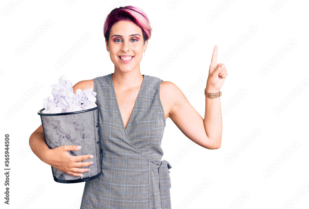 Obraz premium Young beautiful woman with pink hair holding paper bin full of crumpled papers surprised with an idea or question pointing finger with happy face, number one