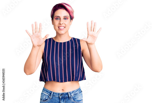Young beautiful woman with pink hair wearing casual clothes showing and pointing up with fingers number ten while smiling confident and happy.