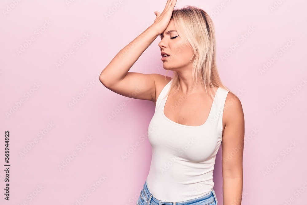 Young beautiful blonde woman wearing casual t-shirt standing over isolated pink background surprised with hand on head for mistake, remember error. Forgot, bad memory concept. Young beautiful blonde woman wearing casual t-shirt standing over isolated pink background surprised with hand on head for mistake, remember error. Forgot, bad memory concept.