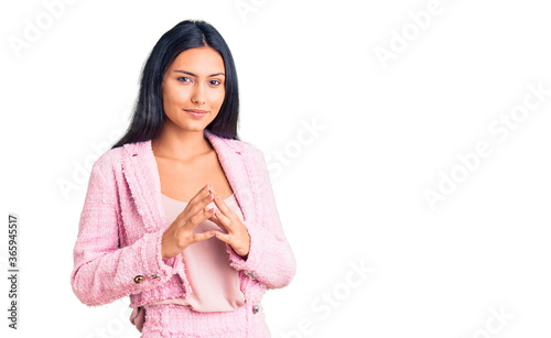 Young beautiful latin girl wearing business clothes hands together and fingers crossed smiling relaxed and cheerful. success and optimistic