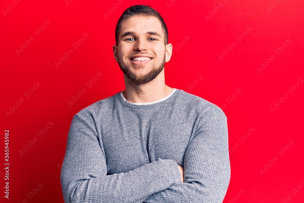 Young handsome man wearing casual sweater happy face smiling with crossed arms looking at the camera. positive person. Young handsome man wearing casual sweater happy face smiling with crossed arms looking at the camera. positive person.