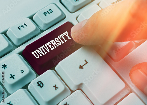 Writing note showing University. Business concept for an educational institution designed to teach and investigate White pc keyboard with empty note paper above white key copy space photo