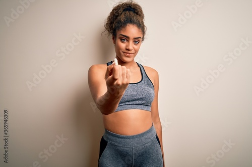 Young african american sportswoman doing sport wearing sportswear over white background Beckoning come here gesture with hand inviting welcoming happy and smiling
