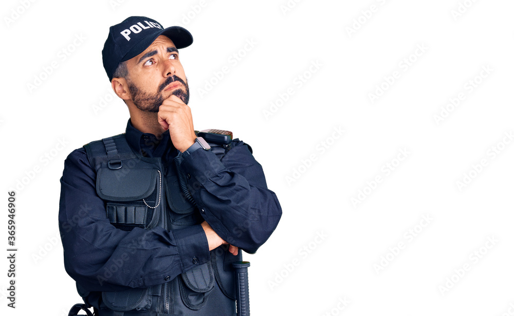 Young hispanic man wearing police uniform with hand on chin thinking about question, pensive expression. smiling with thoughtful face. doubt concept. Young hispanic man wearing police uniform with hand on chin thinking about question, pensive expression. smiling with thoughtful face. doubt concept.