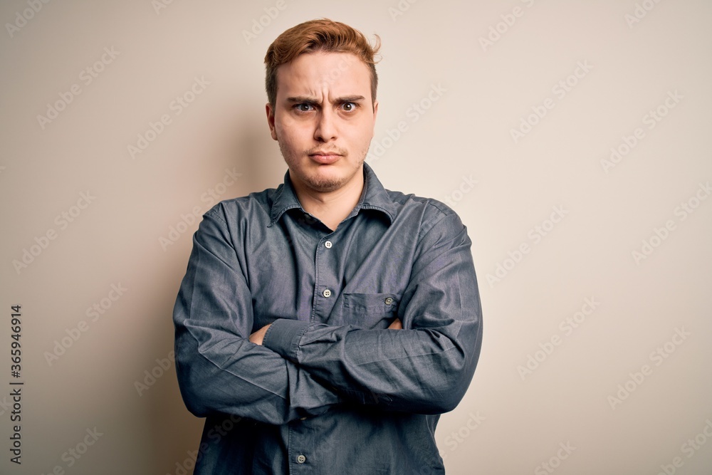 Fototapeta premium Young handsome redhead man wearing casual shirt standing over isolated white background skeptic and nervous, disapproving expression on face with crossed arms. Negative person.