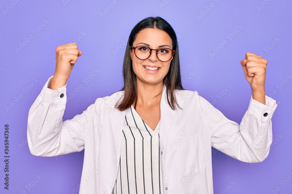 Young beautiful brunette psychologist woman wearing coat and glasses over purple background celebrating surprised and amazed for success with arms raised and open eyes. Winner concept. Young beautiful brunette psychologist woman wearing coat and glasses over purple background celebrating surprised and amazed for success with arms raised and open eyes. Winner concept.