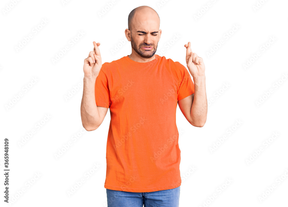 Young handsome man wering casual t shirt gesturing finger crossed smiling with hope and eyes closed. luck and superstitious concept. Young handsome man wering casual t shirt gesturing finger crossed smiling with hope and eyes closed. luck and superstitious concept.