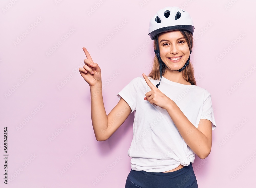 Young beautiful girl wearing bike helmet smiling and looking at the camera pointing with two hands and fingers to the side. Young beautiful girl wearing bike helmet smiling and looking at the camera pointing with two hands and fingers to the side.