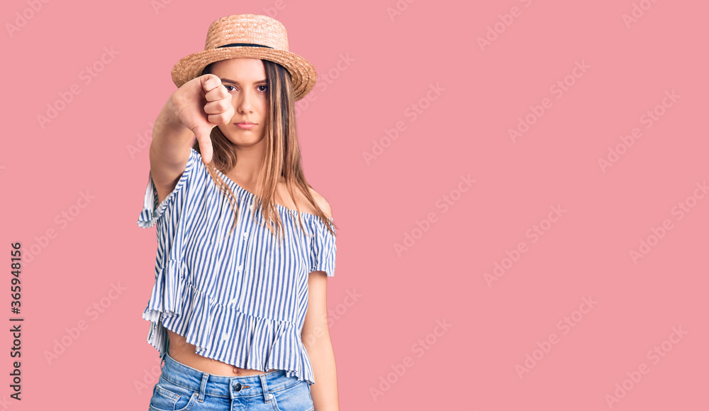 Young beautiful girl wearing hat and t shirt looking unhappy and angry showing rejection and negative with thumbs down gesture. bad expression. Young beautiful girl wearing hat and t shirt looking unhappy and angry showing rejection and negative with thumbs down gesture. bad expression.