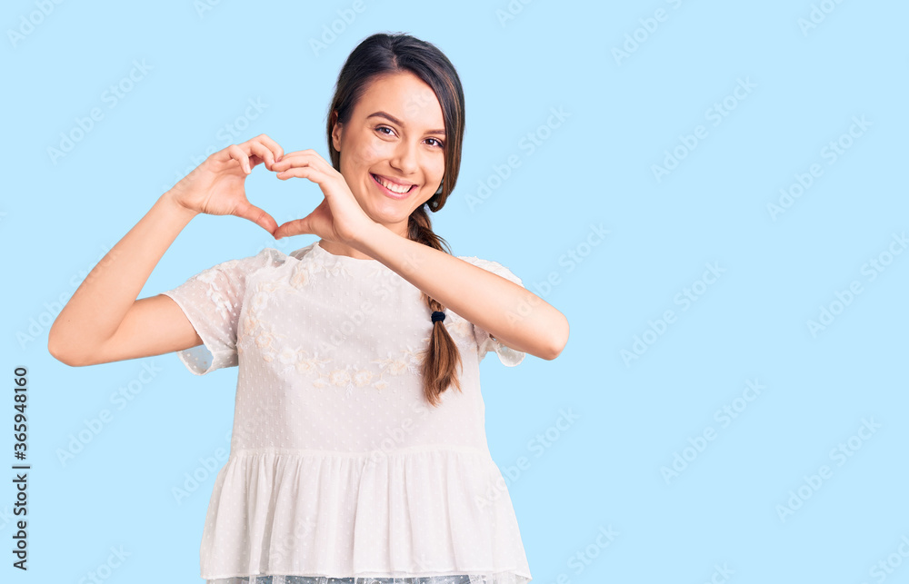 Young beautiful girl wearing casual t shirt smiling in love showing heart symbol and shape with hands. romantic concept. Young beautiful girl wearing casual t shirt smiling in love showing heart symbol and shape with hands. romantic concept.