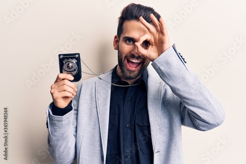 Young handsome man with beard holding police badge smiling happy doing ok sign with hand on eye looking through fingers © Krakenimages.com