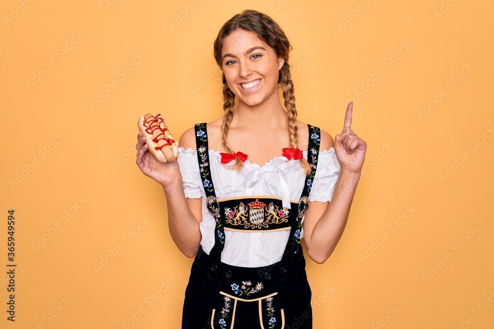 Beautiful blonde german woman with blue eyes wearing oktoberfest dress eating hot dog surprised with an idea or question pointing finger with happy face, number one Beautiful blonde german woman with blue eyes wearing oktoberfest dress eating hot dog surprised with an idea or question pointing finger with happy face, number one