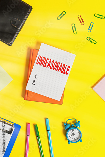 Conceptual hand writing showing Unreasonable. Concept meaning beyond right or acceptability boundaries or behaving in a way Pile of empty papers with copy space on the table photo