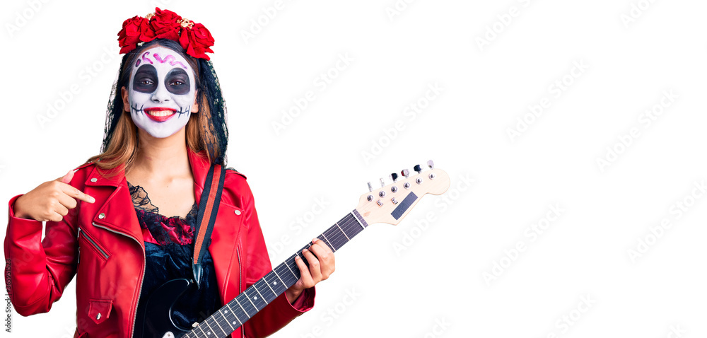 Woman wearing day of the dead costume playing electric guitar pointing finger to one self smiling happy and proud Woman wearing day of the dead costume playing electric guitar pointing finger to one self smiling happy and proud