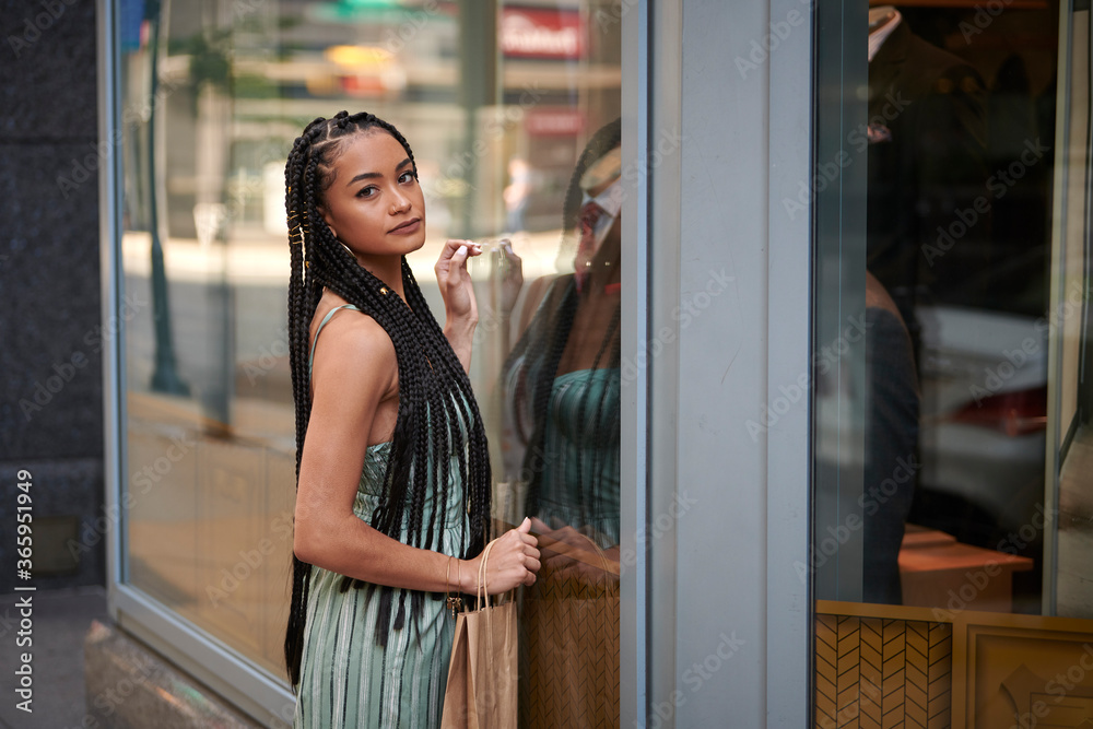 Stunning young biracial woman shops in city while wearing a striped romper Stunning young biracial woman shops in city while wearing a striped romper