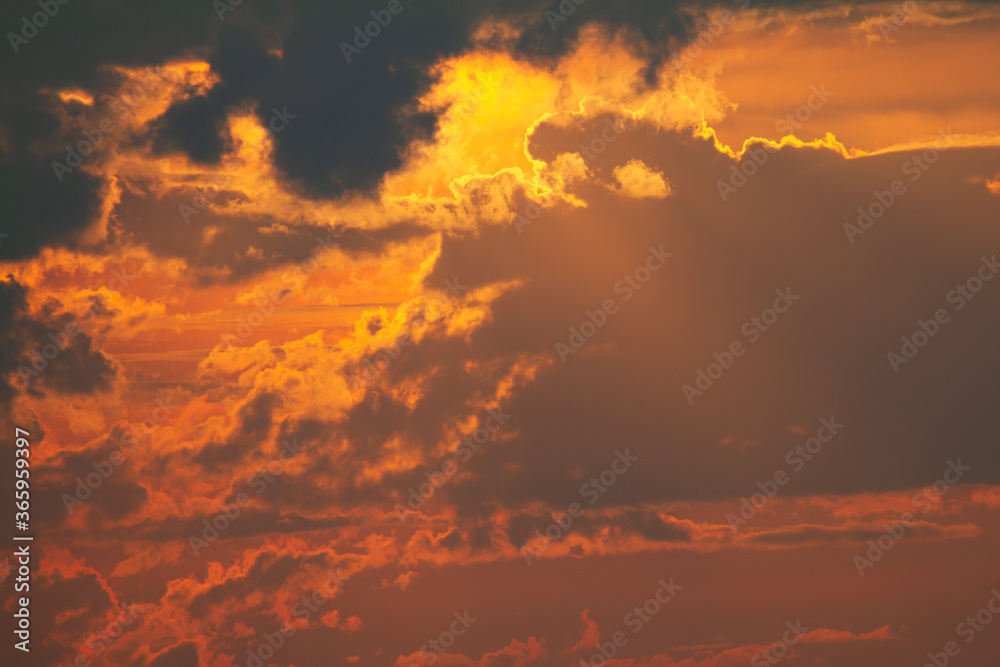 An abstract image of the clouds at sunset. Image was taken with a telephoto lens with the sun behind the  clouds creating rim lighting.  Details of the random dark and light patches of clouds are seen