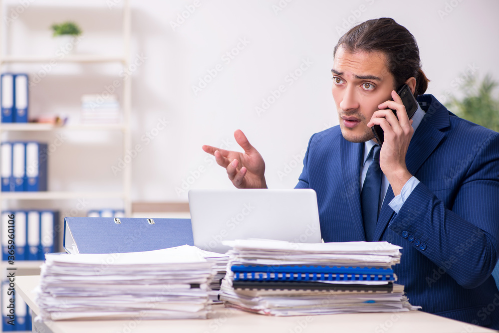 Young male employee unhappy with excessive work Young male employee unhappy with excessive work
