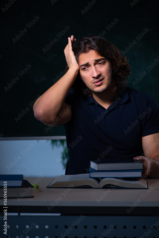 Young male student in the classroom at night
