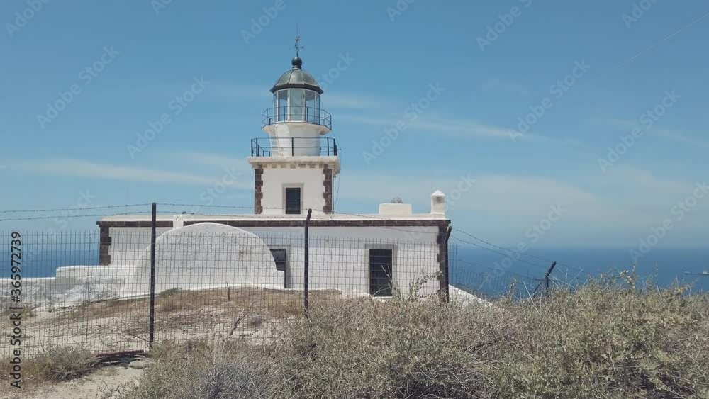 Santorini, Greece. Akrotiri Lighthouse on the southern of Thira island in Greek Islands on a clear, sunny day with bright, blue sky Santorini, Greece. Akrotiri Lighthouse on the southern of Thira island in Greek Islands on a clear, sunny day with bright, blue sky