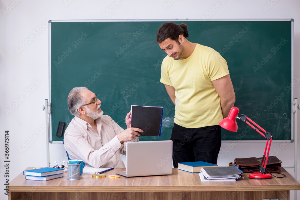 Old teacher and young male student in the classroom