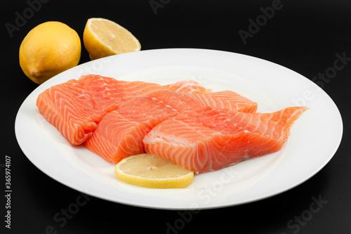 Omega 3 rich foods and lunch preparation concept with photograph of raw salmon piece on plate isolated on black background