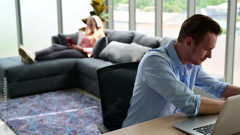 Happy and relax lifestyle of young couple lover wearing casual dress together working on laptop notebook computer in living room at home. Positive relationship concept. Happy and relax lifestyle of young couple lover wearing casual dress together working on laptop notebook computer in living room at home. Positive relationship concept.