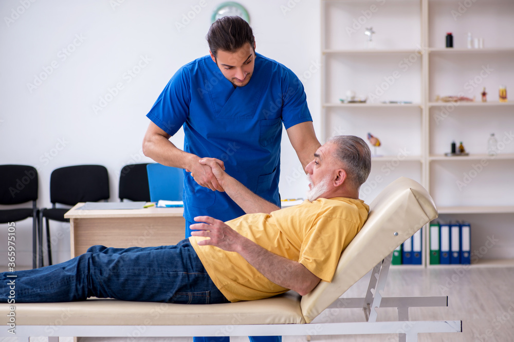 Fototapeta premium Old injured man visiting young male doctor chiropractor