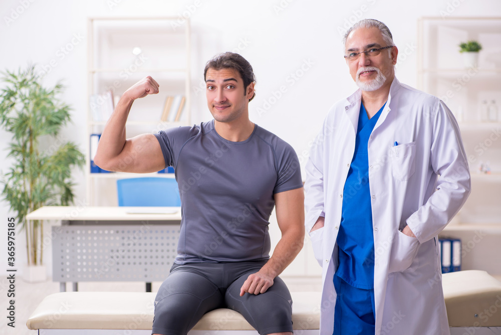 Young male patient visiting old doctor traumatologist Young male patient visiting old doctor traumatologist