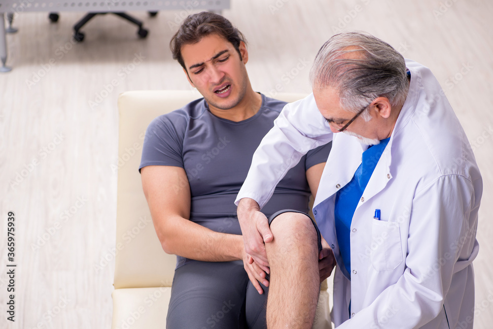 Fototapeta premium Young male patient visiting old doctor traumatologist