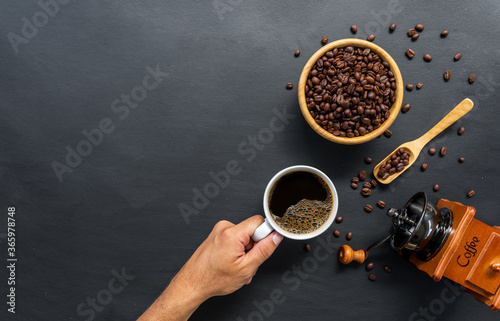hot coffee, bean and hand grinder on black table background. space for text. top view
