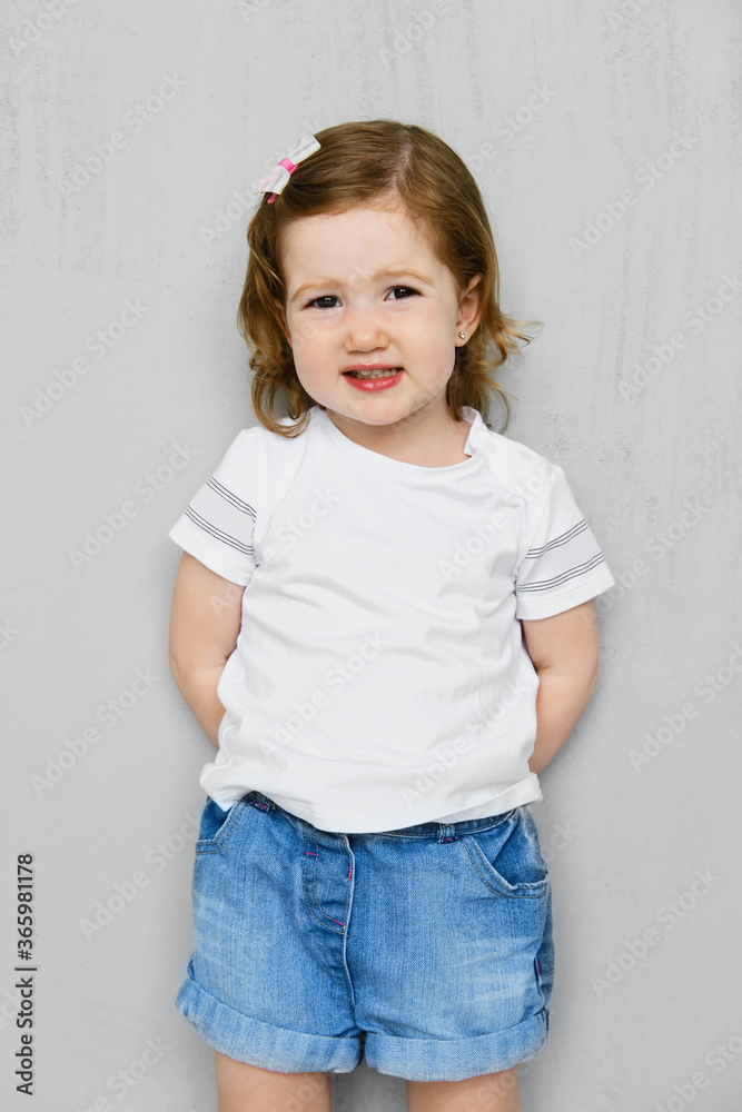 Two years old girl in t-short and jeans shorts posing in studio Two years old girl in t-short and jeans shorts posing in studio