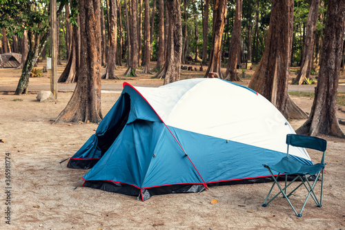 Camping Tent and Resting Chair at Campsite on Nature Pine Forest Background  Family Vacation and Outdoor Leisure Activity Camp Fire in National Park. Natural Adventure Backpacking and Holiday Trip.