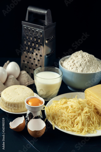  Wheat flour, few types of cheese, milk, eggs, grater – preparation for making pie, pizza, baking. Process of cooking Adjaruli Khachapuri. Adjarian Khachapuri Recipe – Georgian cheese bread. © Grigoriy