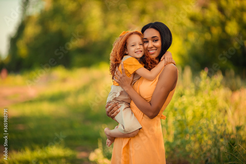 International family: happy cheerful mother and daughter on a summer walk in the park