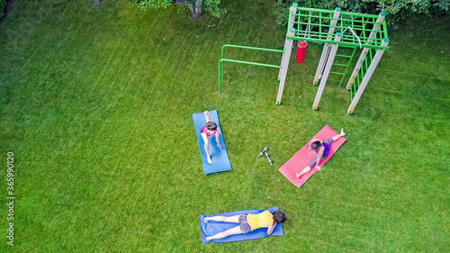 Family fitness and sport outdoors, active mother and children doing workout in park aerial top view from above 