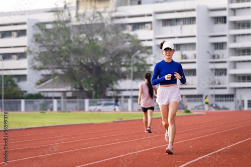 Young fitness woman runner jogging excercise in the morning on city stadium track in the city. Female athlete excercise in the city stadium to keep body fitness. Health and recreation stock photo.