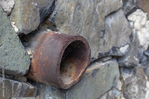 Картината върху платно old iron drainpipe made of granite wall.