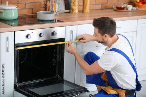 Worker repairing oven in ki...