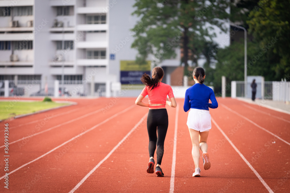 Young fitness woman runner jogging excercise in the morning on city stadium track in the city. Female athlete excercise in the city stadium to keep body fitness.  Stock photo.