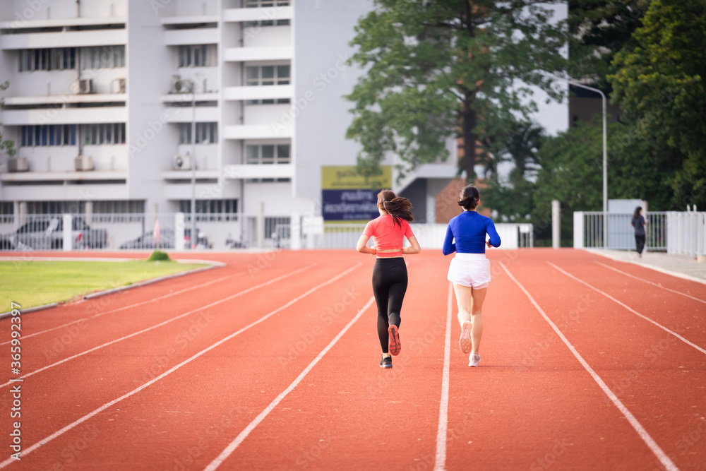 Obraz premium Young fitness woman runner jogging excercise in the morning on city stadium track in the city. Female athlete excercise in the city stadium to keep body fitness. Stock photo.