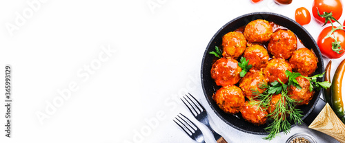 Meatballs with tomato sauce and spices in frying pan on white kitchen table background. Panoramic banner with copy space