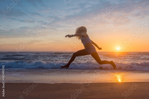 pretty young woman jumping on the beach at sunset