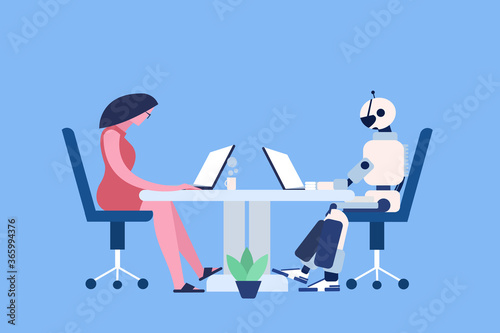 A human and a robot working on their laptops sharing the same table