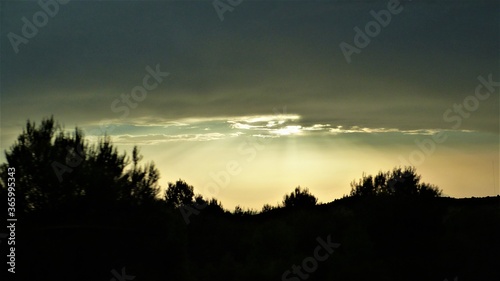 Atardecer con nubens color gris y blanca con sol sobresaliendo entre ellas