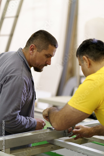 Profession, carpentry, woodwork and people concept - two carpenterswork with wood for furniture at workshop. photo