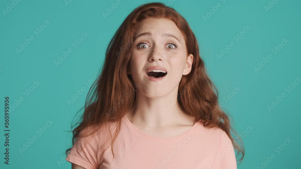 Portrait of pretty excited redhead girl surprisingly looking in camera over colorful background. Wow expression