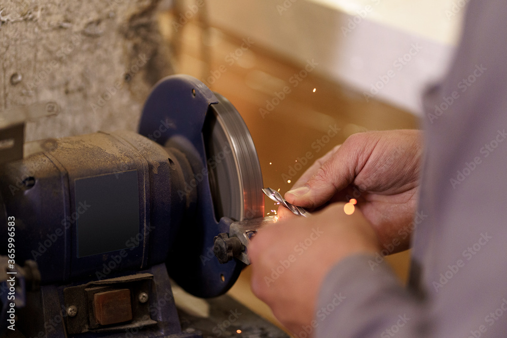 Samolepka The hands of an engineering young man regrinding the drill tool for sharpen the drill tool with grinding wheel